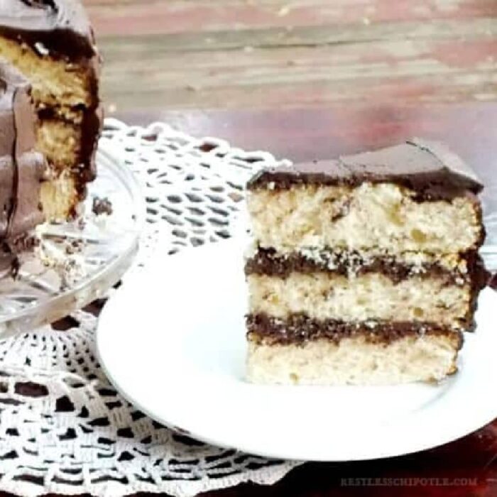 Slice of vanilla layer cake with chocoalte frosting.