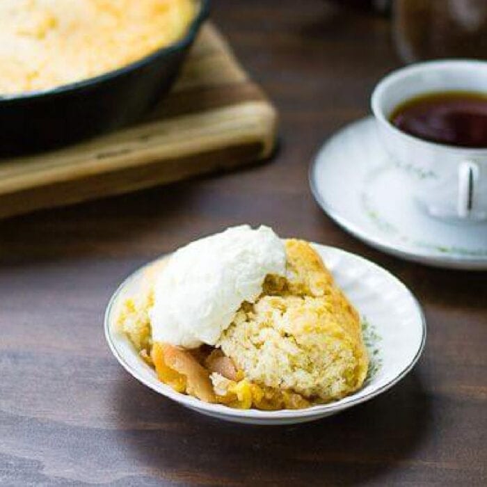 A bowl with a scoop of peach cobbler in it and ice cream on the top.