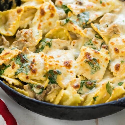 An iron skillet filled with the finished Alfredo Chicken Ravioli.