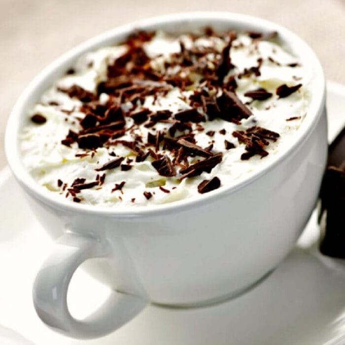 A cup of creamy Irish Coffee with chocolate on top.