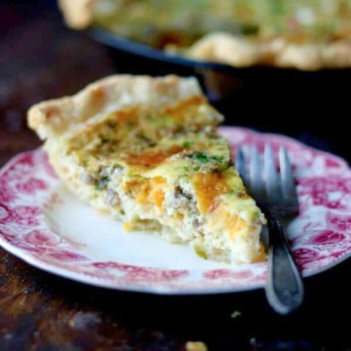 Slice of quiche with sausage and cheese on a plate.