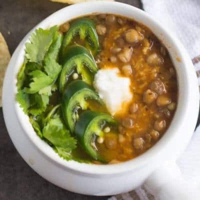 Overhead view of lentil soup garnished with jalapeno and sour cream.