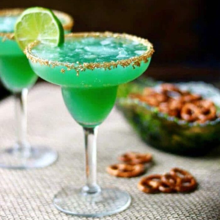 Green margarita in a glass with a gold rim and lime garnish.