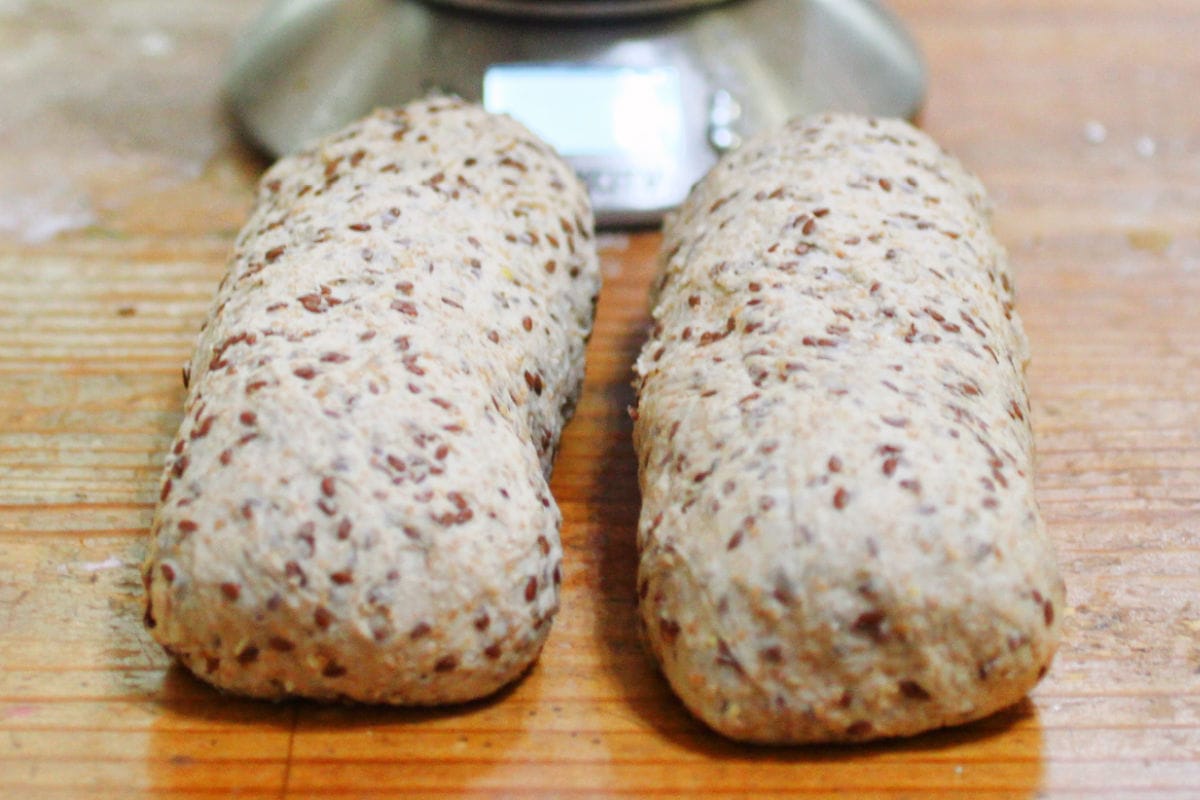 2 multigrain bread loaves resting on the counter after shaping.