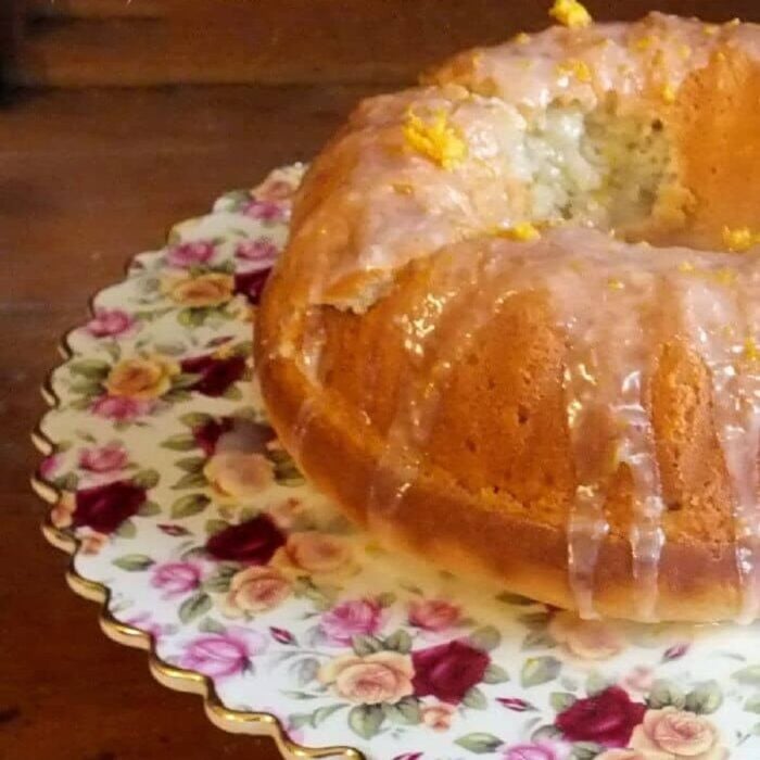 A lemon bundt cake on a flowered cake plate.