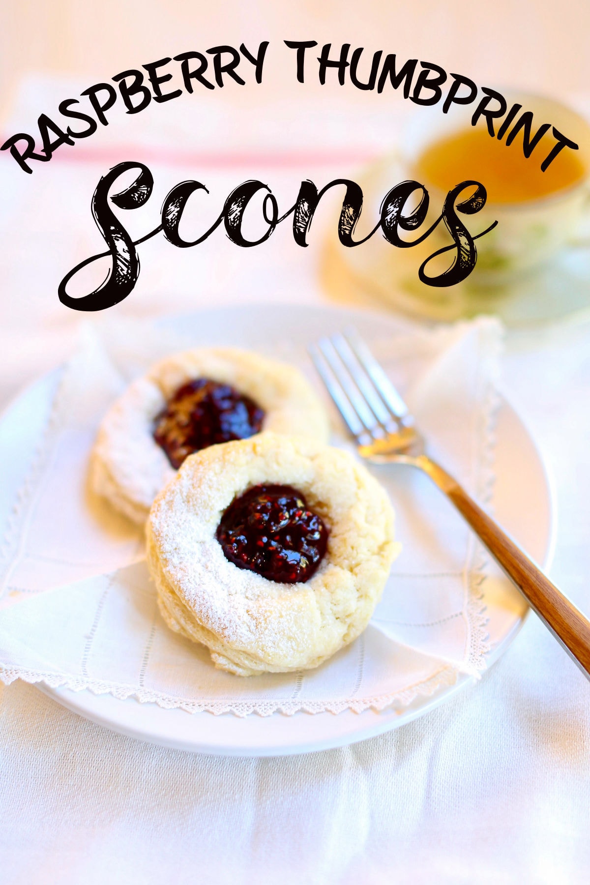 Two raspberry scones on a plate with a fork nearby.