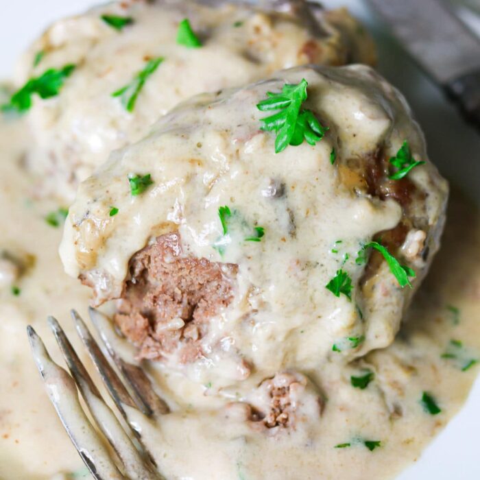 Closeup of salisbury steak on a plate with a bite removied.