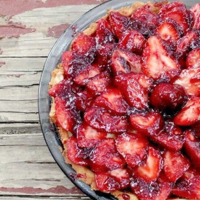 An uncut strawberry tart in a pie dish, seen from the top.