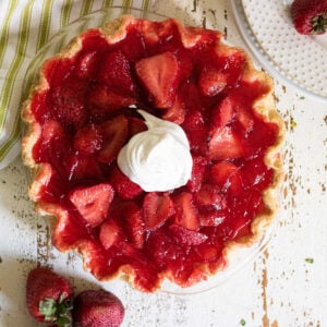 Overhead view of strawberry pie garnished with whipped cream.