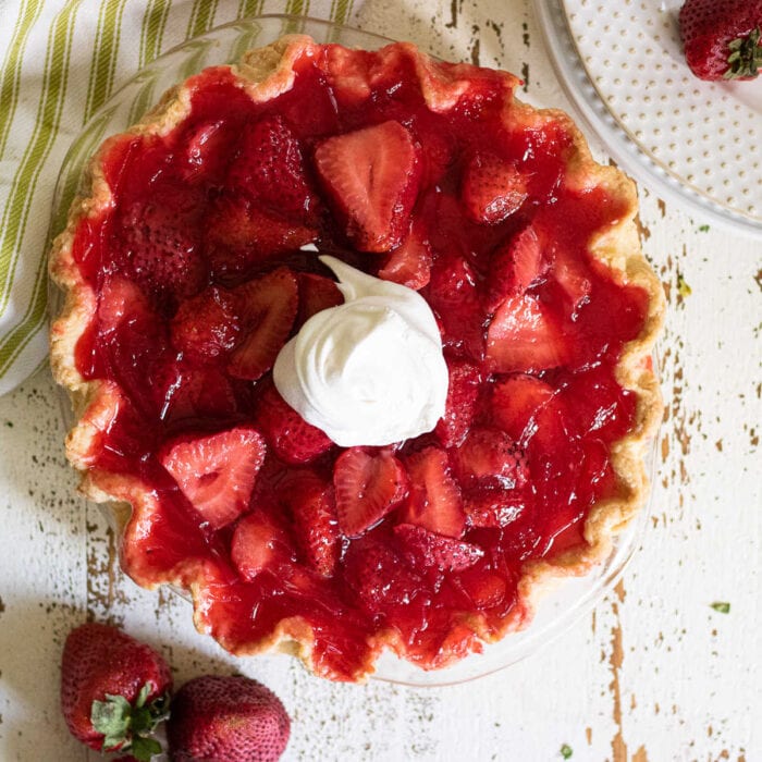Overhead view of strawberry pie garnished with whipped cream.