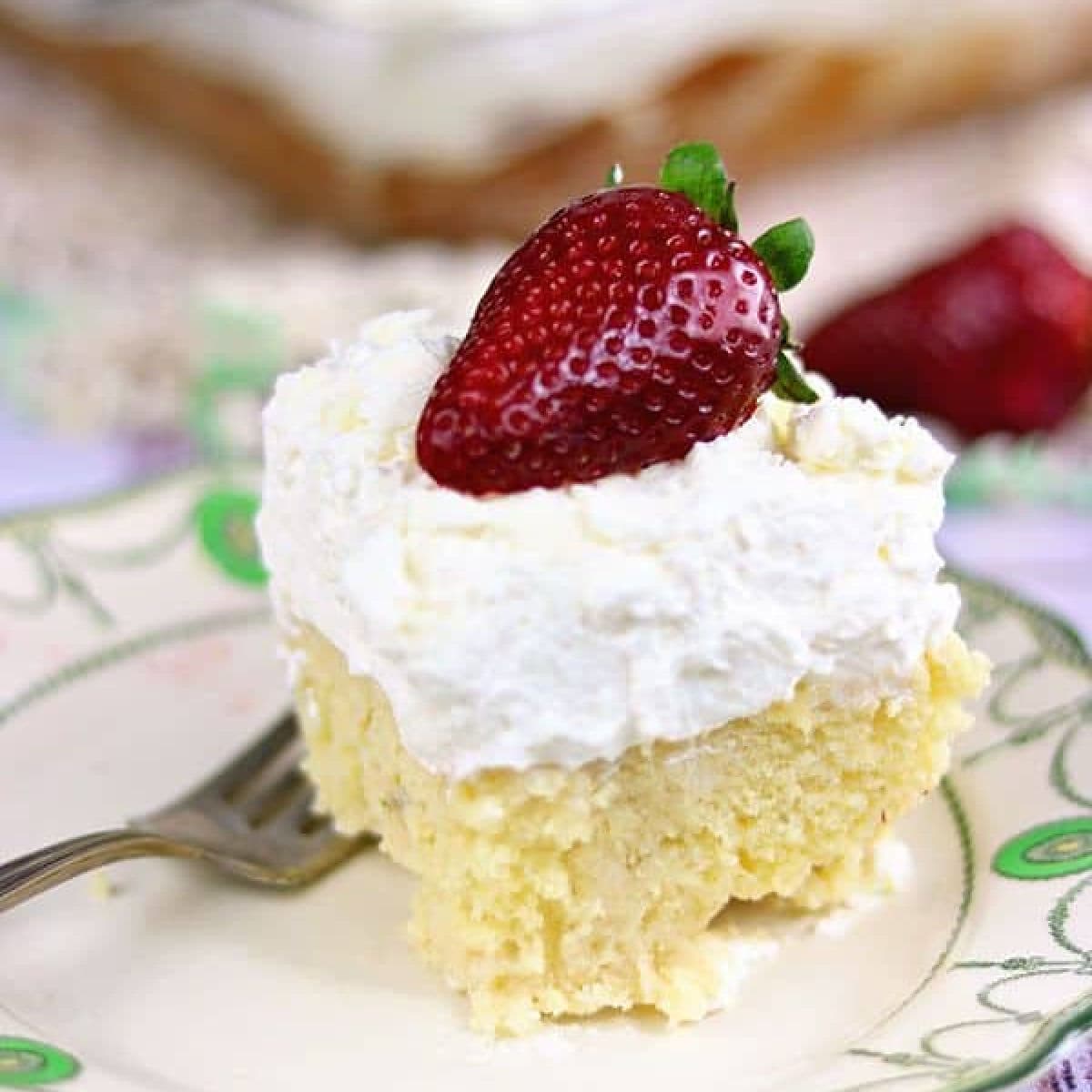 Square of yellow cake with a thick layer of cream on top.