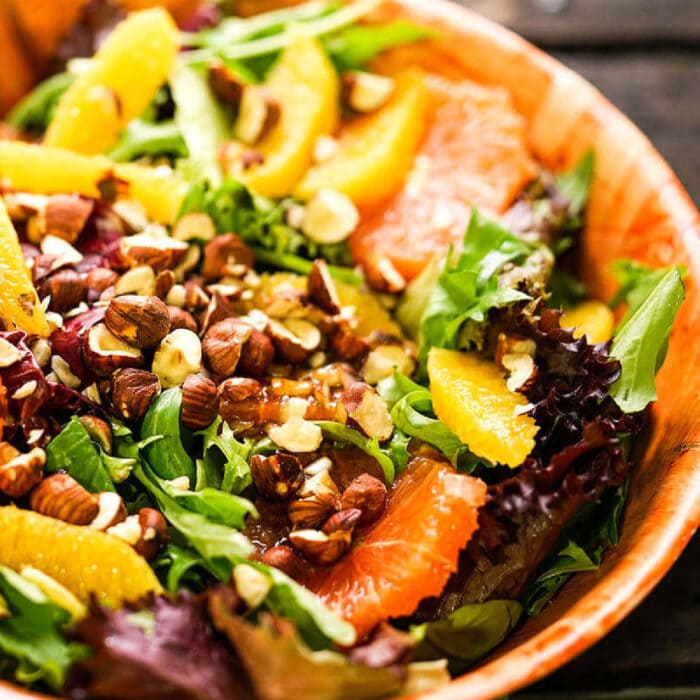 Citrus salad with greens in a wooden bowl.