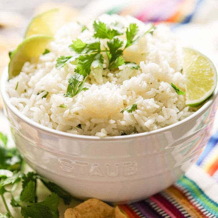 A bowl of rice garnished with cilantro and lime.