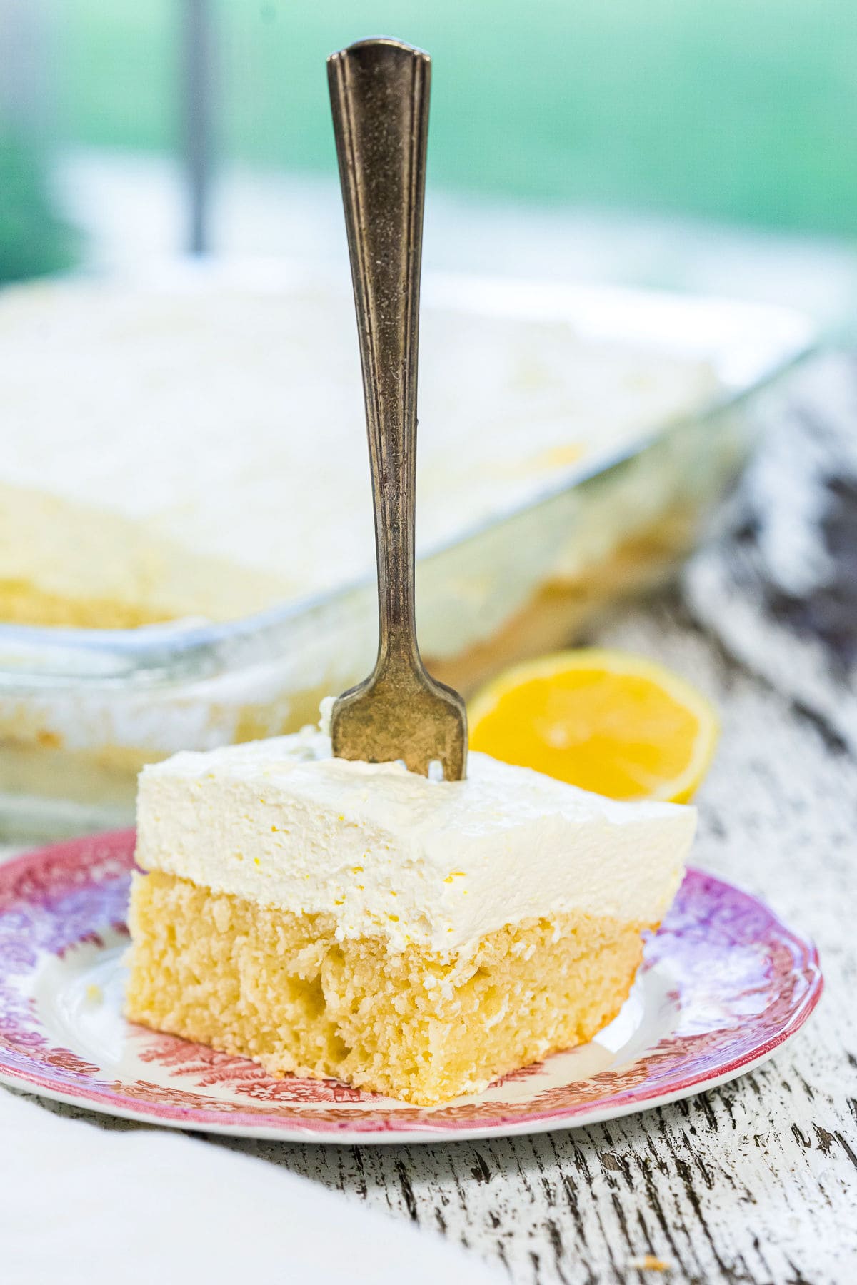 A square of lemon sheet cake with a fork in the center.