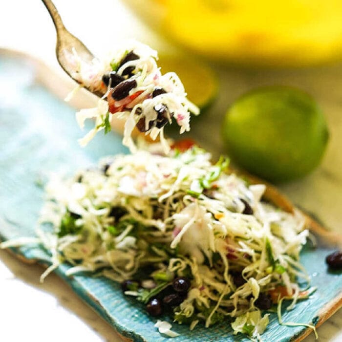 A forkful of Mexican coleslaw being lifted from a plate.