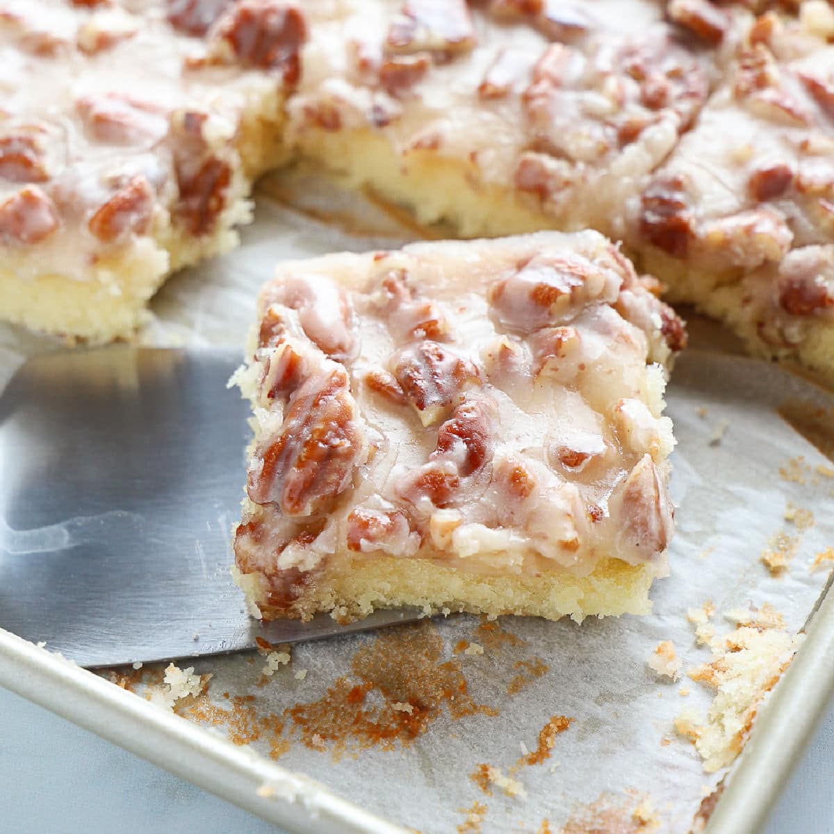 Close up of a square of white Texas sheet cake showing the pecans on the top.