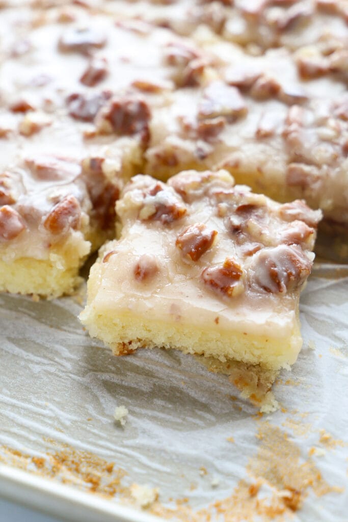 Close up of white Texas sheet cake showing the moist cake and fudgy pecan icing.