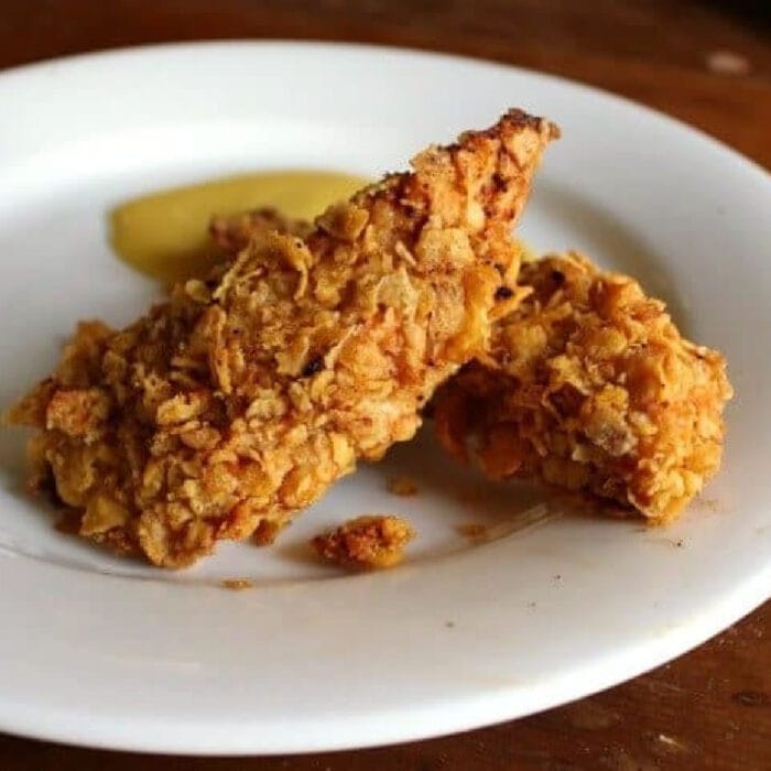 Crispy chicken strips on a white plate.