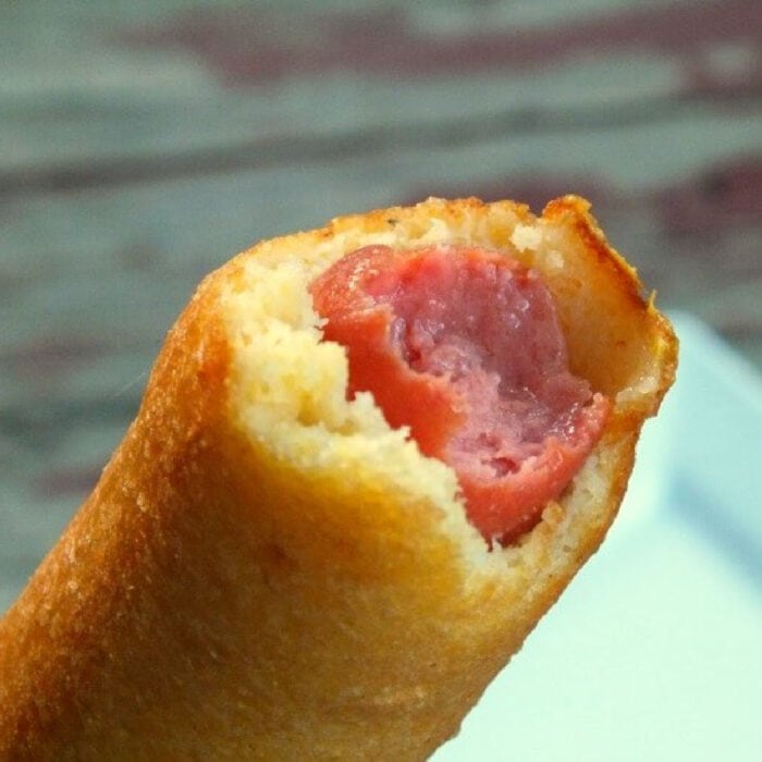 Homemade corn dog with a bite removed.