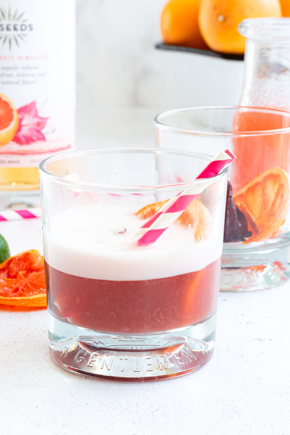 Glass full of the pink cocktail with pink and white striped straws in it.