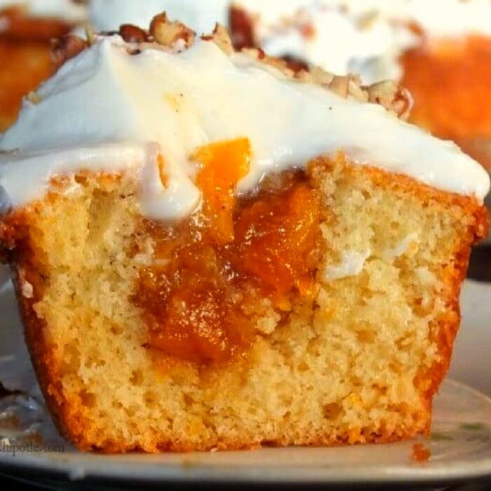 A peach cupcake sliced in half to show the filling.