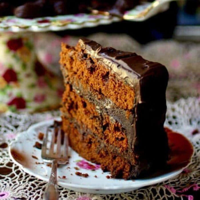 A slice of a triple layer spiced devil's food cake with chocolate frosting.