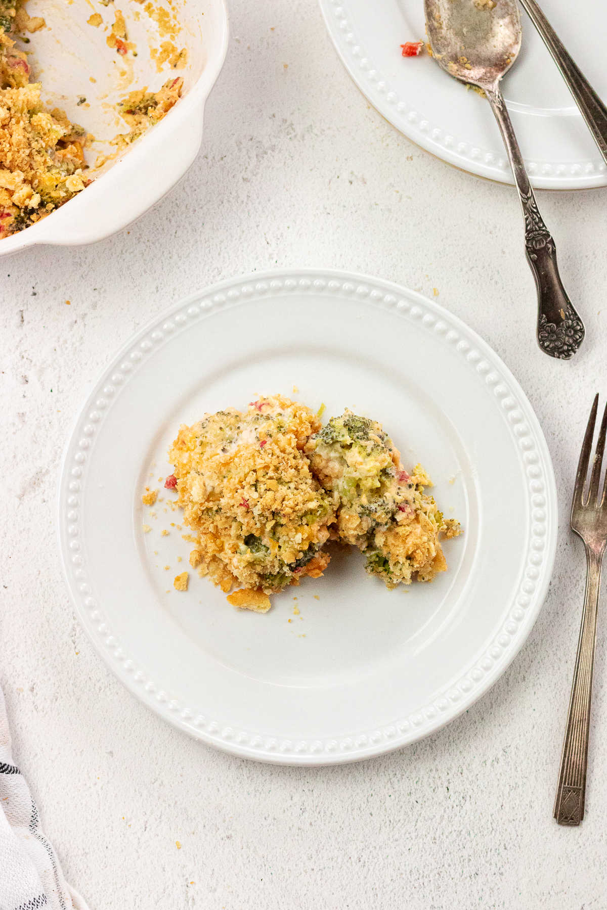 Overhead shot of a serving of broccoli cheese casserole on a white plate.