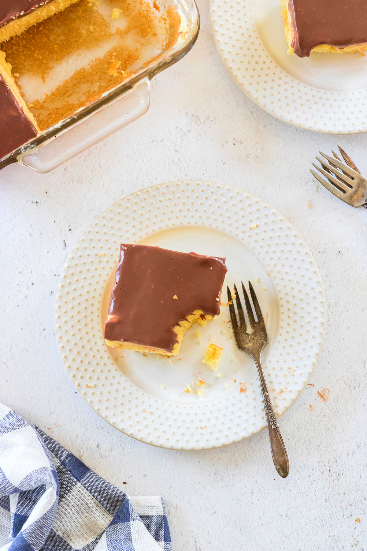 Overhead view of Boston cream pie poke cake on a plate with a fork nearby.