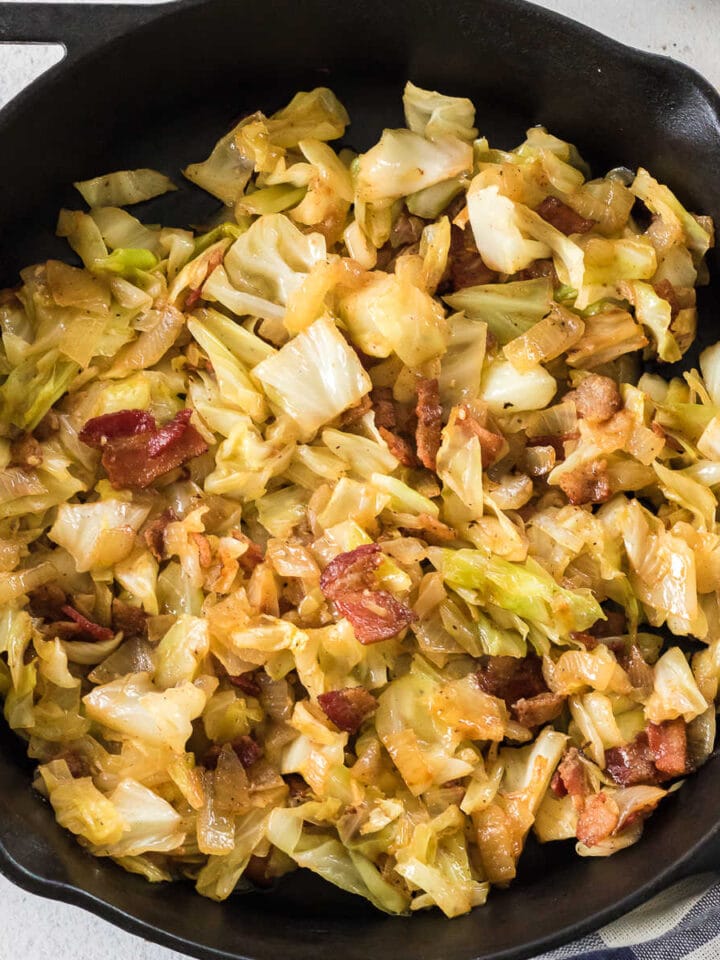 Closeup of fried cabbage and bacon in a skillet.