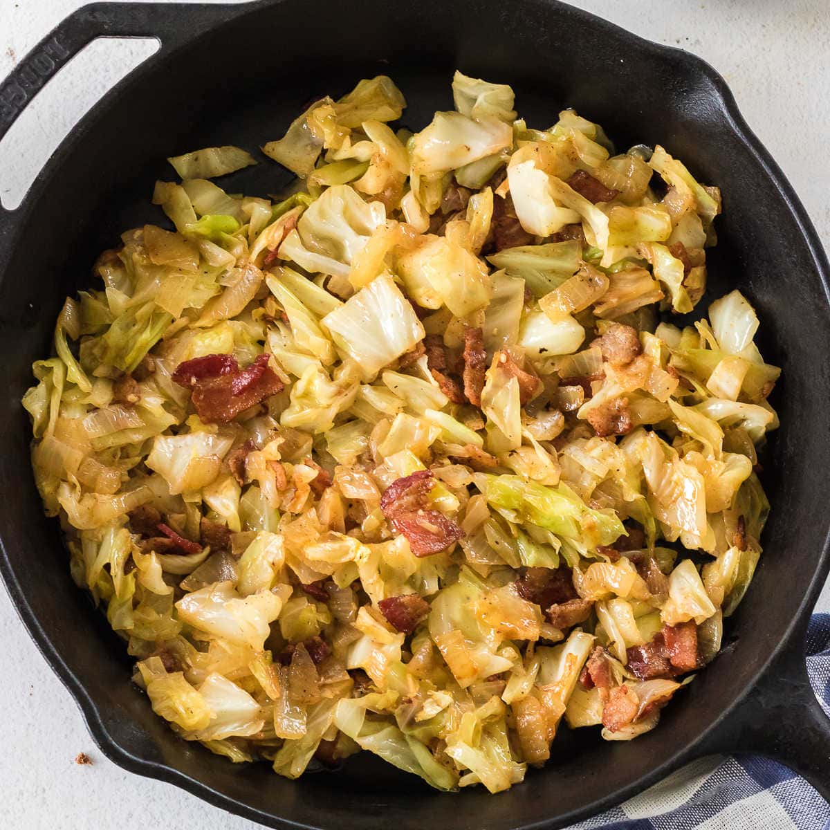 Closeup of fried cabbage and bacon in a skillet.
