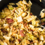 Close up of cabbage and bacon in a skillet with a text overlay for Pinterest.