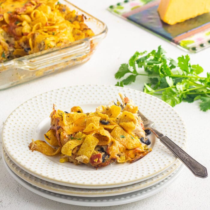 A serving of the finished Frito casserole on a plate with the casserole pan in the background.