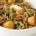 Side view of a serving dish of green beans and potatoes with a text overlay for Pinterest.