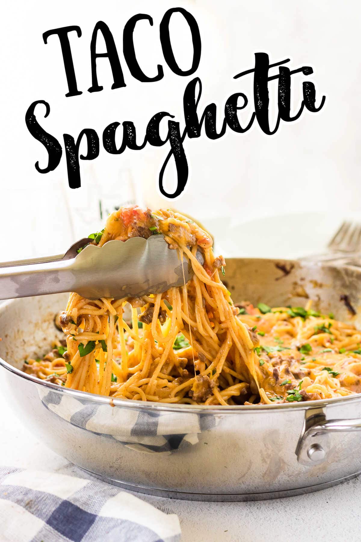 Tongs picking up a serving of taco spaghetti from the dish. Title text overlay.