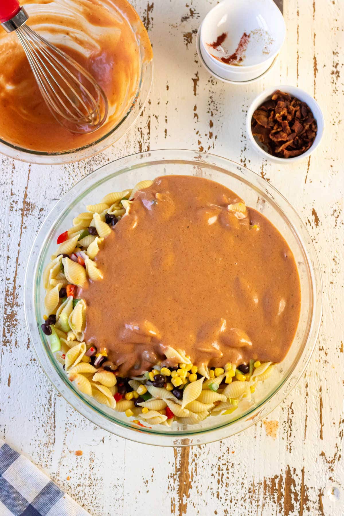 The salad dressing poured on top of the macaroni salad ingredients.
