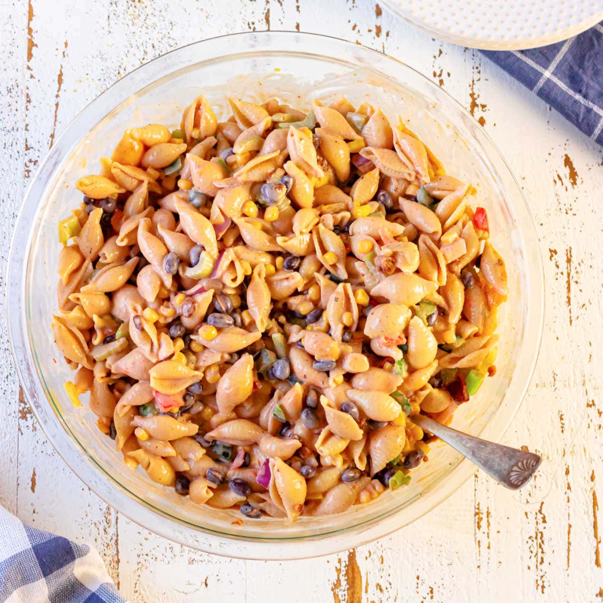 Closeup overhead view of the macaroni salad in a bowl with a spoon in it for serving.