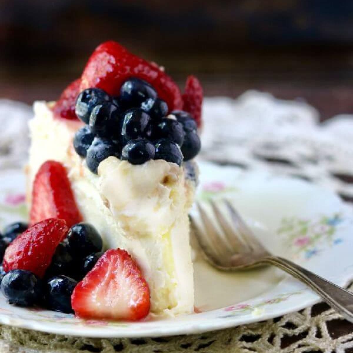 Slice of cheesecake with strawberries and blueberries on top.