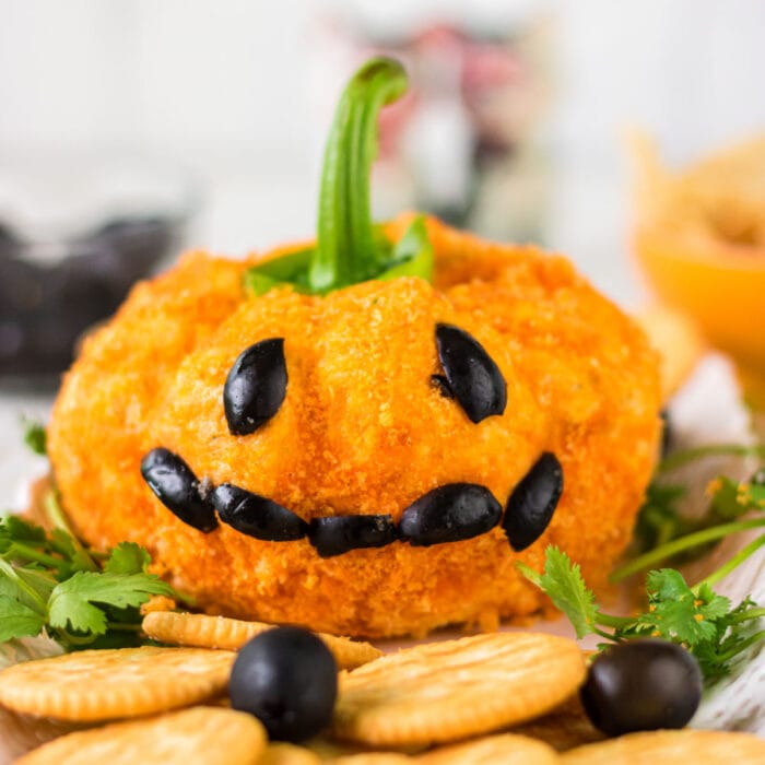 Close up of a cheeseball that looks like a Jack-o-lantern.