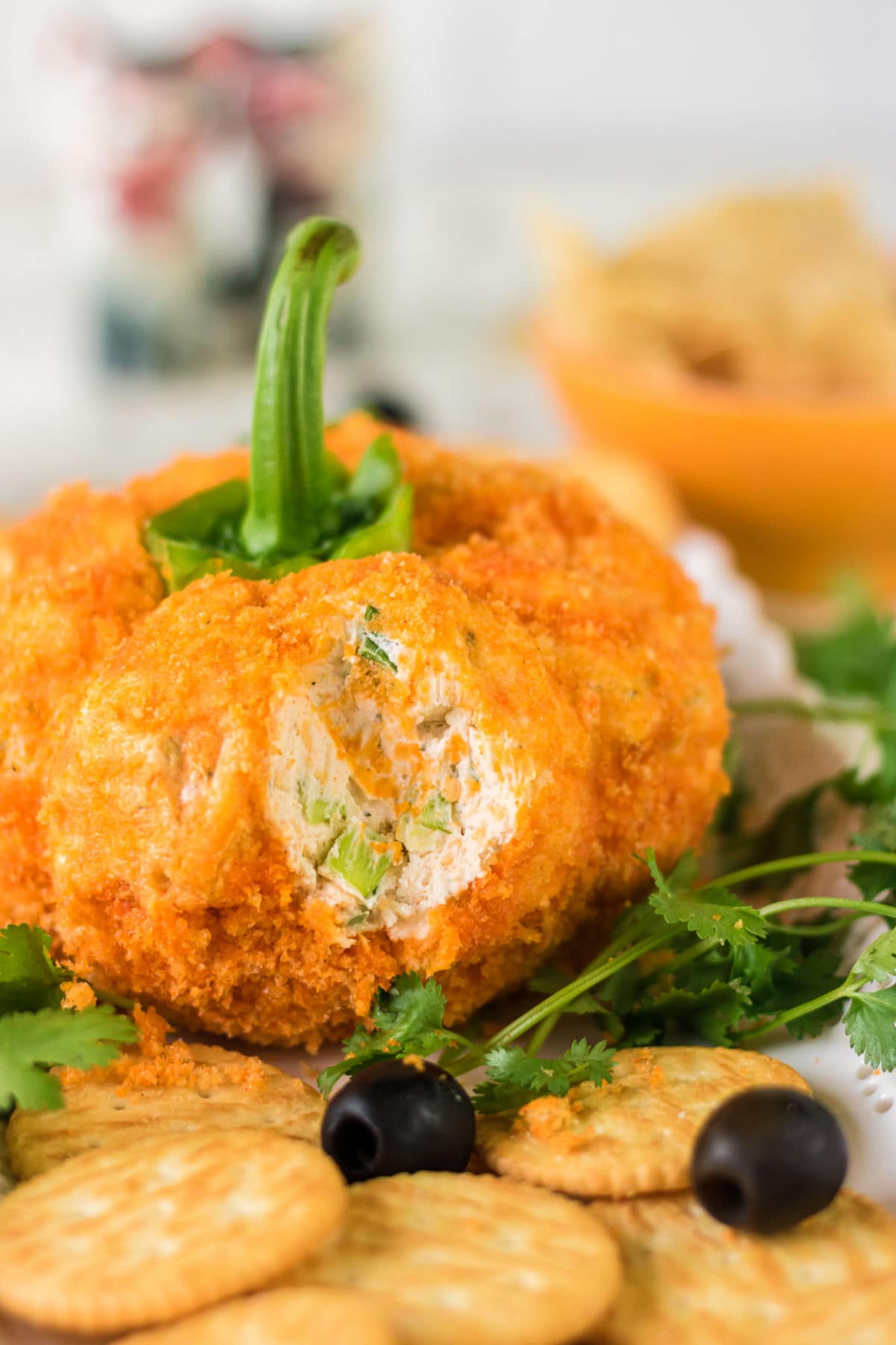 Side view of the cheeseball surrounded by crackers cut open to show the interior texture.