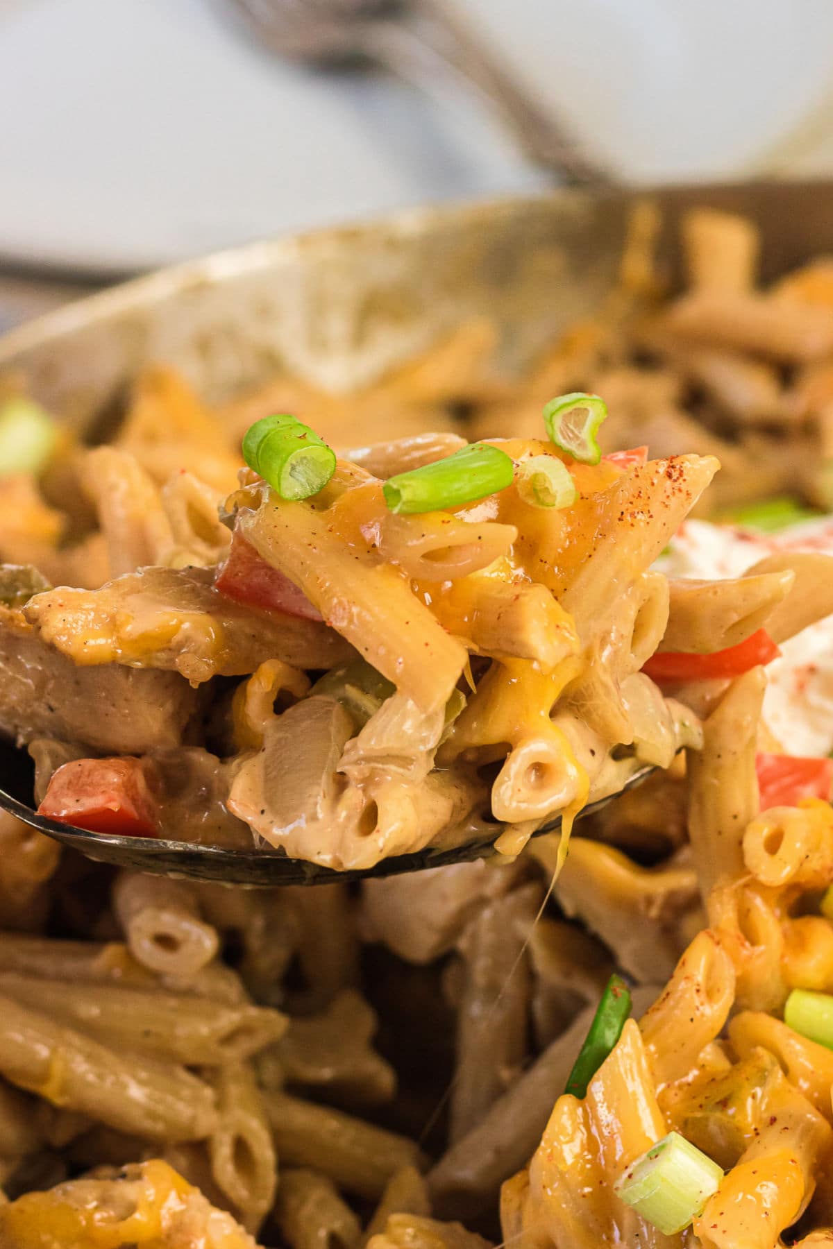 Closeup of a serving of chicken fajita pasta being removed from a pan.