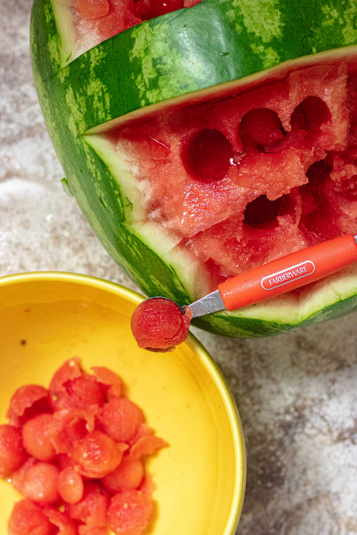 A melon baller spoon being used to create melon balls.