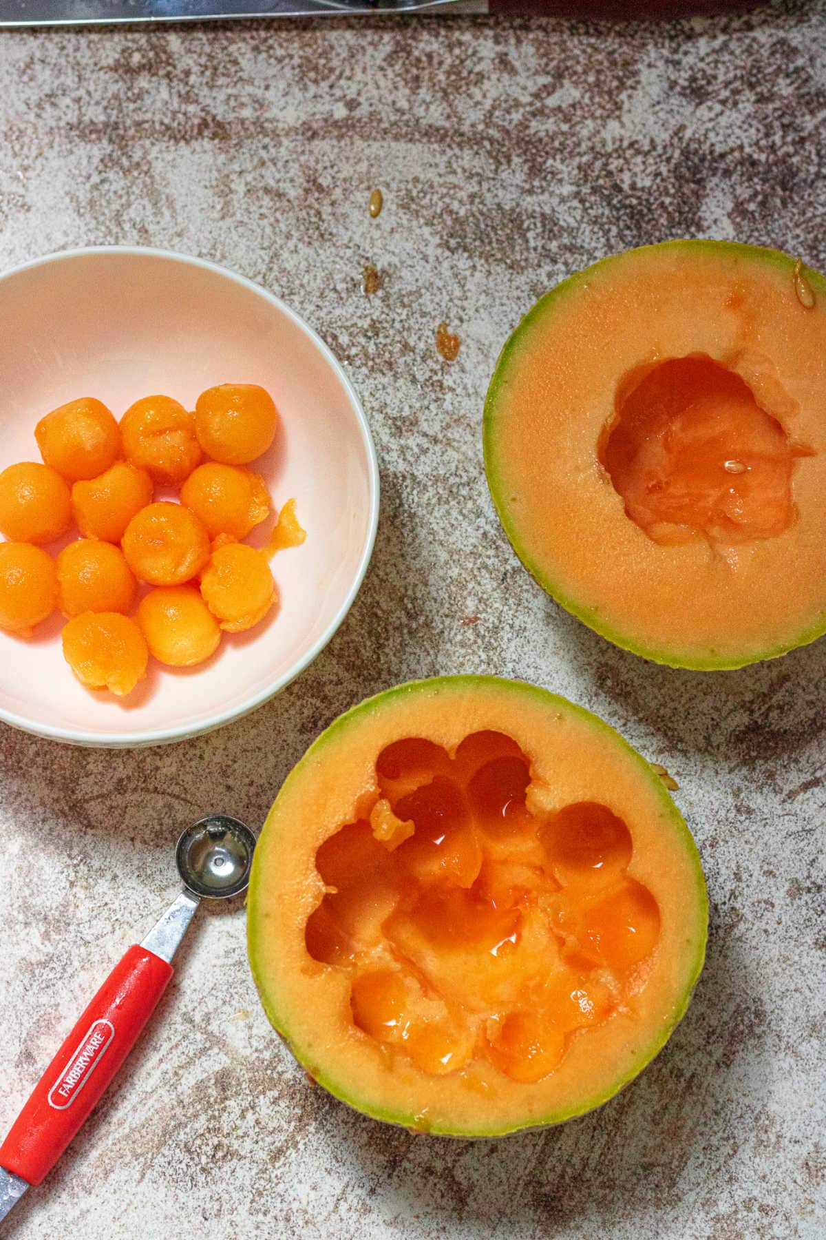 A cantaloupe being cut into melon balls.