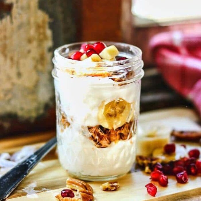 A jar with layers of yogurt and pecans.