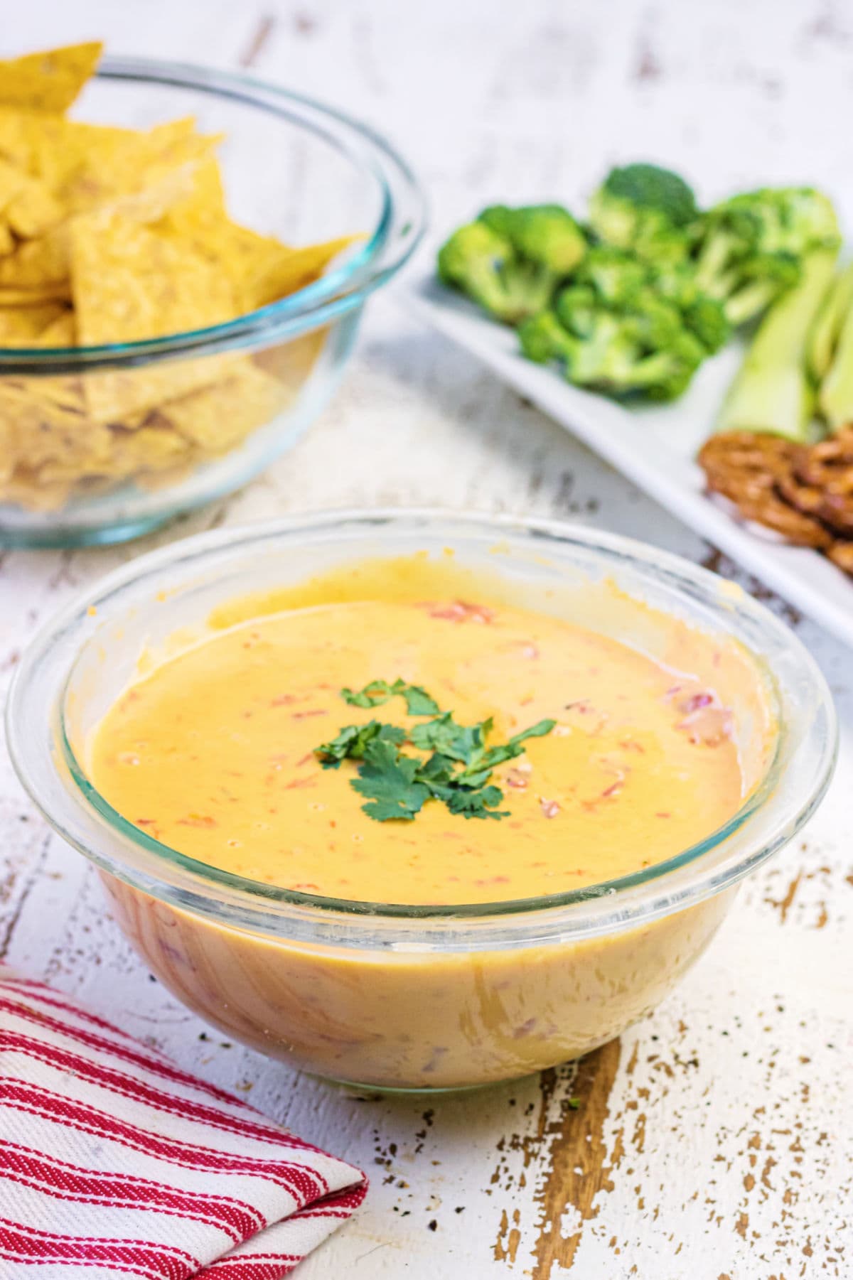 Decorative image. Bowl of queso on a table with chips behind it.