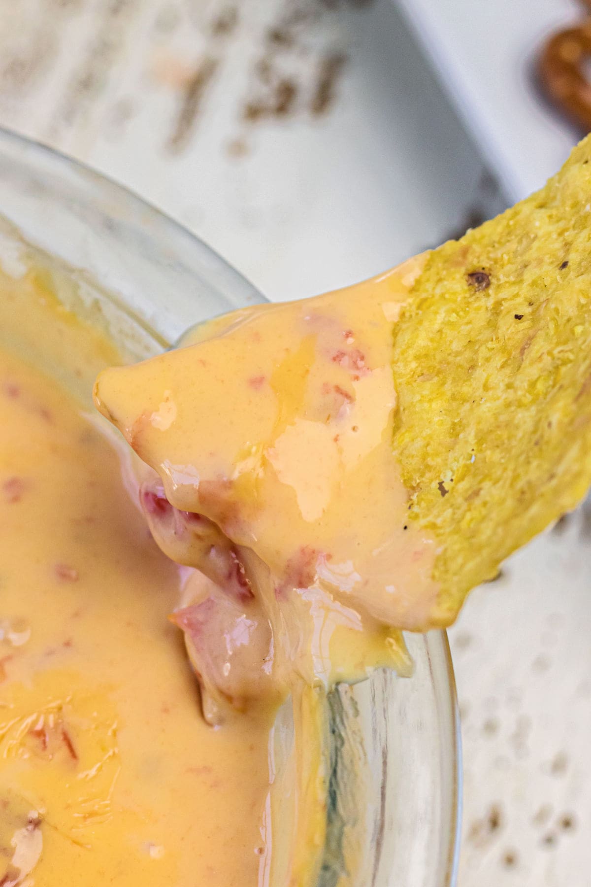 A tortilla chip being dipped into the queso.