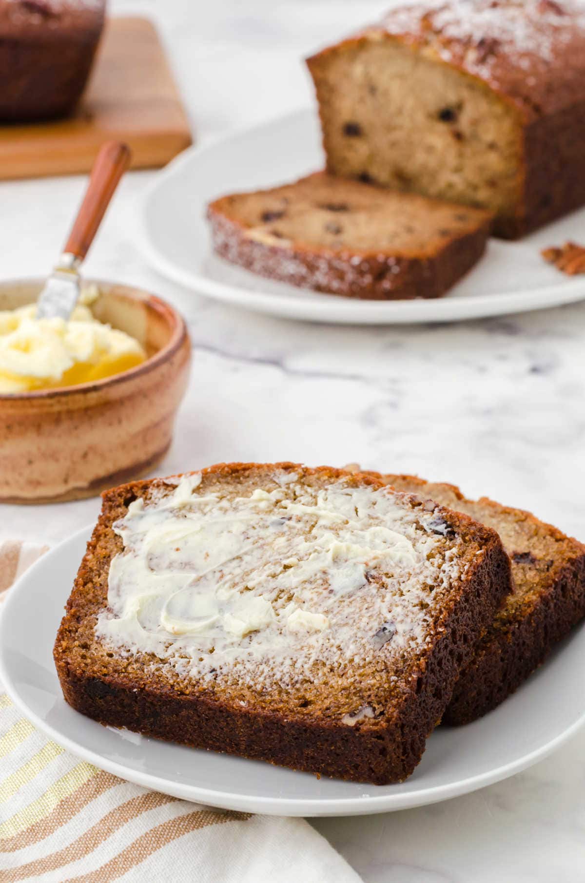 Slices of banana bread on a plate with butter spread over them.