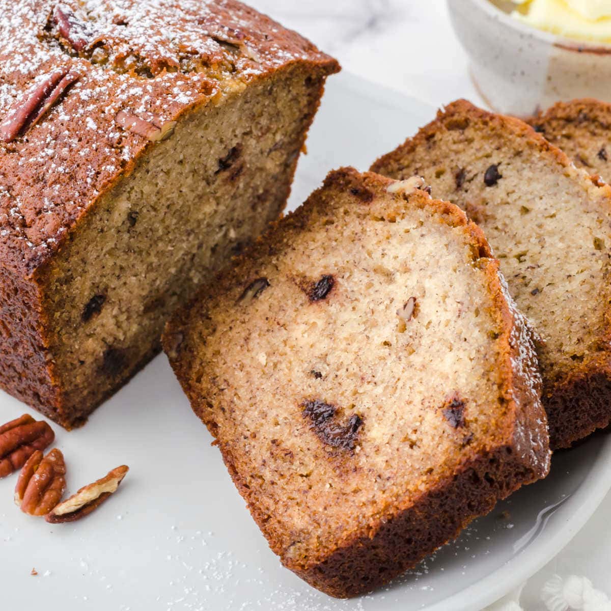 Slice of buttermilk banana bread showing the pecans and chocolate chips.