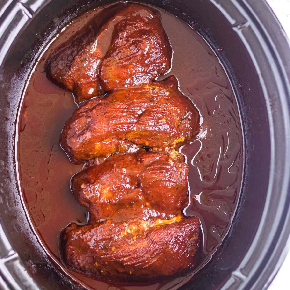 Overhead view of the finished meat in a slow cooker.