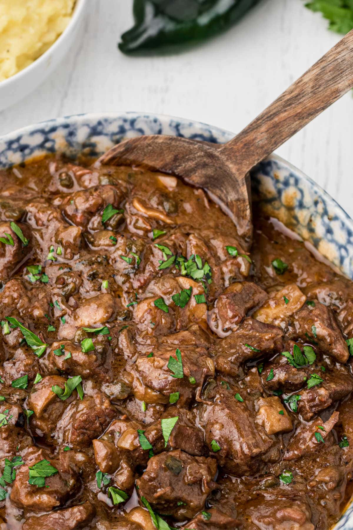 A close up of a spoon serving beef tips from a pot