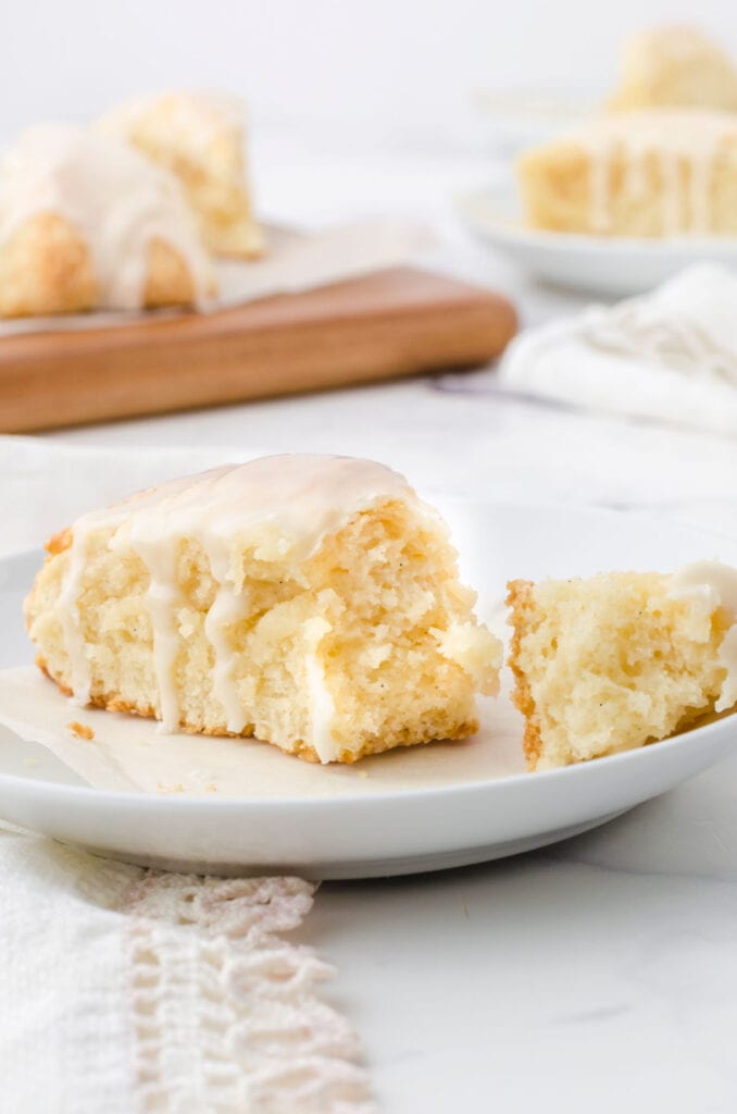 A scone on a plate with the tip broken off.